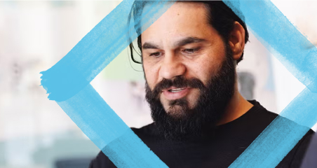 1. A bearded man stands next to a blue square, showcasing a modern and minimalist design aesthetic.