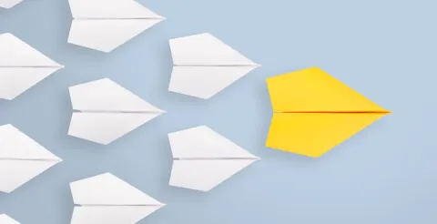 Paper planes representing innovative ideas, with a standout yellow plane symbolizing unique creative leadership.