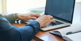 Analyst typing on a keyboard while reviewing recent corporate mergers and future industry trends.