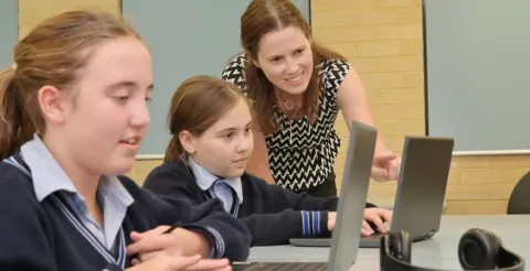 Teacher guiding primary school students through classroom activities in an engaging learning environment.